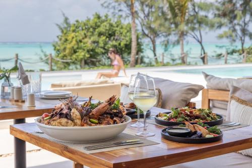 a table with a bowl of food and a glass of wine at Kaskazi Hotel Zanzibar in Jambiani