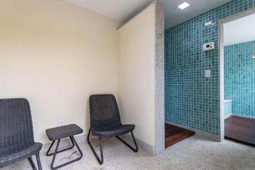 two chairs and a shower in a room with green tile at Vaca do Brejo, piscina aquecida, sauna, A/C quente in Petrópolis
