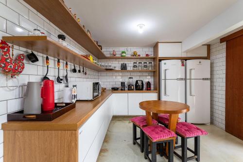 a kitchen with white appliances and a table and two refrigerators at Vaca do Brejo, piscina aquecida, sauna, A/C quente in Petrópolis