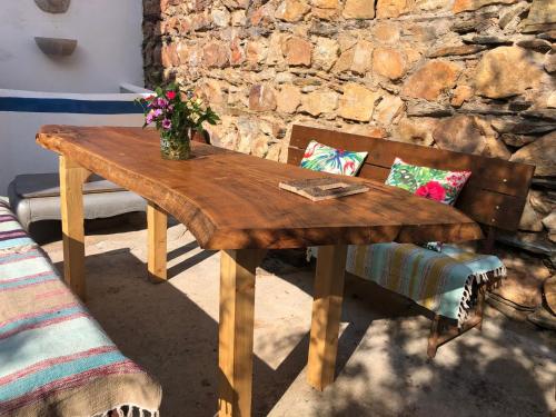 a wooden table with a vase of flowers on it at Casas de Alegrete - Castelo by Portus Alacer in Alegrete