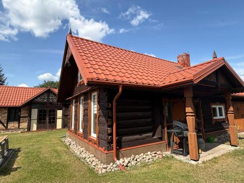 a log cabin with a red roof at Dom wakacyjny Kołodno 