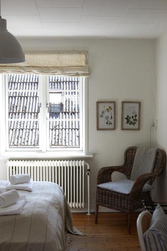 a bedroom with a bed and a chair and a window at Hotel Saxkjøbing in Sakskøbing