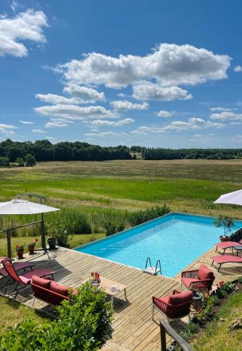 - une piscine avec des chaises et des parasols sur une terrasse en bois dans l'établissement Le Presbytere, à Castex