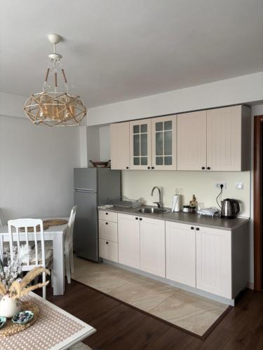 a kitchen with white cabinets and a sink and a table at Apartman DBB Nikšić in Nikšić