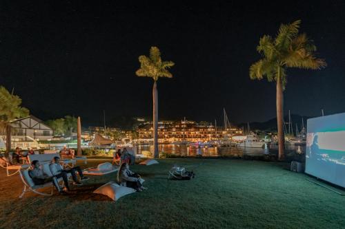 a group of people sitting in chairs on a field with palm trees at The Bannister Hotel & Yacht Club by Mint in Santa Bárbara de Samaná