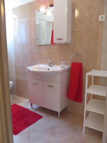 a bathroom with a sink and a red towel at Apartments Luka in Pakoštane
