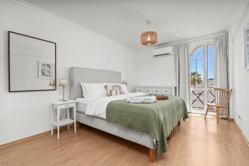 a white bedroom with a large bed and a window at Elegant Flat with Pool & Balcony by HostWise in Tavira