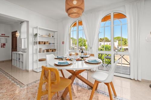 a white dining room with a white table and chairs at Elegant Flat with Pool & Balcony by HostWise in Tavira