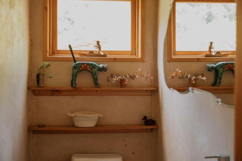 a bathroom with a toilet and two windows and a sink at Casa Awänímä - Luxury Permaculture Hotel & Eco-Retreat in Tzununá