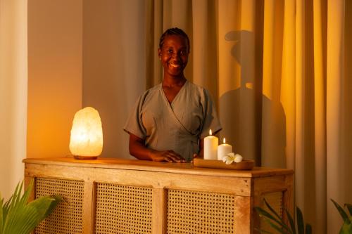 a woman standing behind a table with candles at Kaskazi Hotel Zanzibar in Jambiani