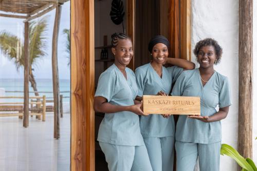 three women in blue scrubs holding a box at Kaskazi Hotel Zanzibar in Jambiani