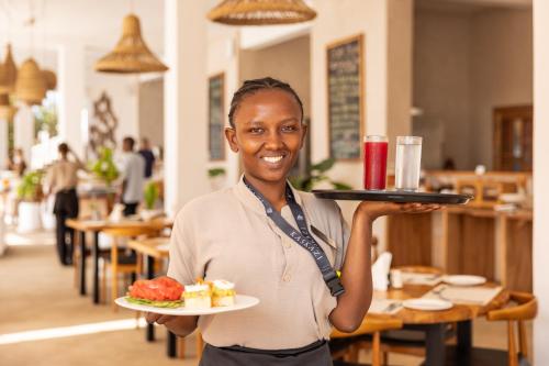a woman holding a plate of food in a restaurant at Kaskazi Hotel Zanzibar in Jambiani
