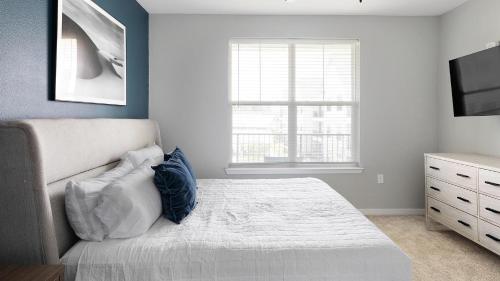 a bedroom with a bed and a dresser and a window at Landing at FarmHaus - Huntsville in Madison