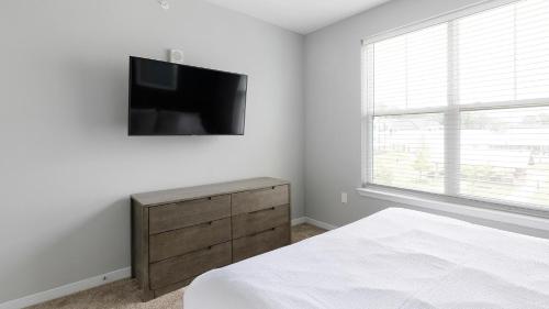 a bedroom with a bed and a television on a wall at Landing at FarmHaus - Huntsville in Madison