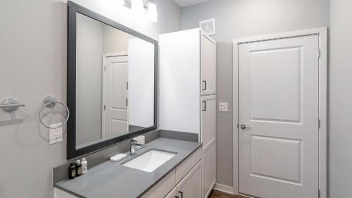 a bathroom with a sink and a large mirror at Landing at FarmHaus - Huntsville in Madison