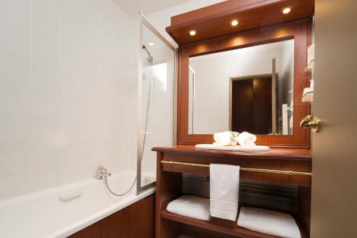 une salle de bain avec un lavabo, un miroir et une baignoire dans l'établissement Hotel Ker Juliette, à Pornichet