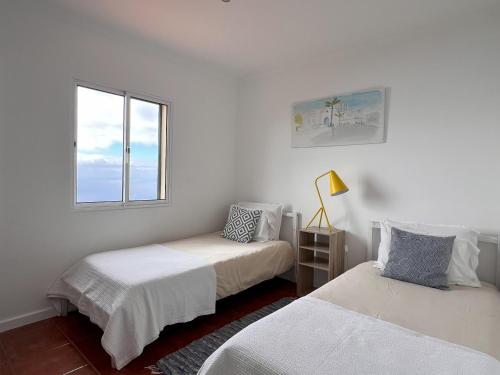 zwei Betten in einem weißen Zimmer mit Fenster in der Unterkunft Casa da Ovelha I Madeira in Fajã da Ovelha