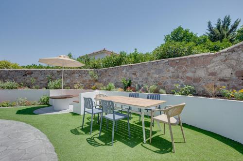 a patio with a table and chairs on grass at Secret Garden Studios in Mytilini