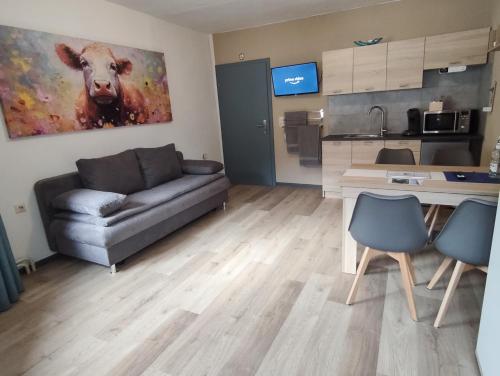 a living room with a couch and a cow painting on the wall at Pension am Kirchberg - Zimmer 2 in Daun