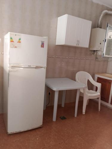 a kitchen with a white refrigerator and a table at Morjene Résidence in Hammam Sousse