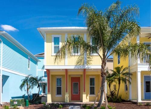 a yellow house with a red door and palm trees at Parrotfish Place - Stay for 6 in Orlando