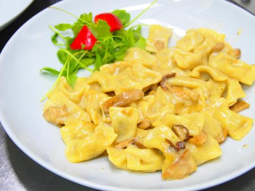 un plato de pasta con setas y una ensalada en Gostišče Jazbec, en Kobarid