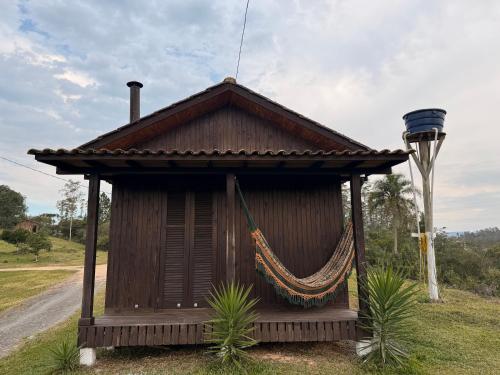 a small building with a hammock in the grass at CABANAS BELVEDERE- SERRA DO RIO Do RASTRO in Louro Müller