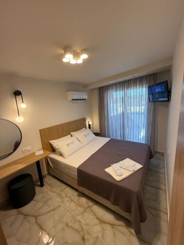 Un dormitorio con una cama, un escritorio y un televisor. en Hellenikon Suites Malama, en Paralia Katerinis