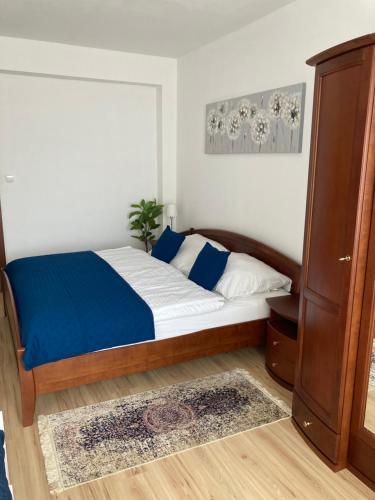 a bedroom with a bed with blue and white sheets at Apartmán KaTry in Veľká Lomnica