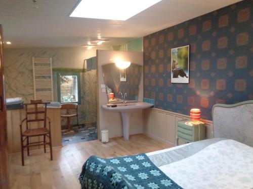 um quarto com uma cama, um lavatório e uma mesa em les couleurs de l'eau em Plonéour-Lanvern