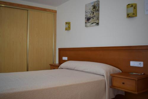 a bedroom with a bed and a wooden headboard at Hotel VIDA Playa Paxariñas in Portonovo