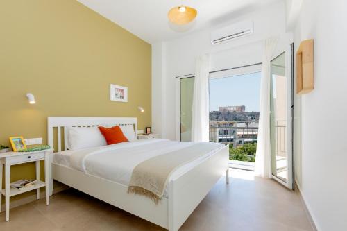 sypialnia z białym łóżkiem i dużym oknem w obiekcie Livinn Acropolis View LV w Atenach