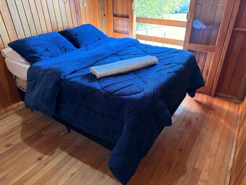 a bed with a blue blanket on top of it at CABANAS BELVEDERE SERRA DO RiO DO RASTRO in Louro Müller