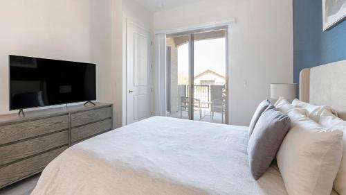 a white bedroom with a large bed and a flat screen tv at Landing at Linda Vista - Oro Valley in Oro Valley