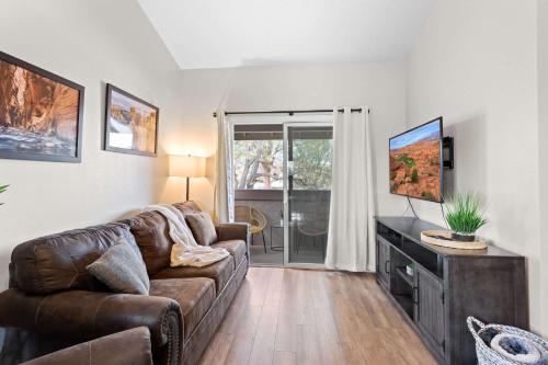 a living room with a couch and a flat screen tv at Hikers Hideaway - Cozy Resort Condo with Pool & More in St. George