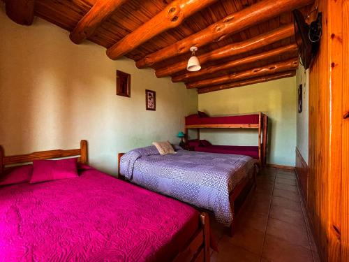 two beds in a room with wooden ceilings at Cabañas Clarita in Dina Huapi