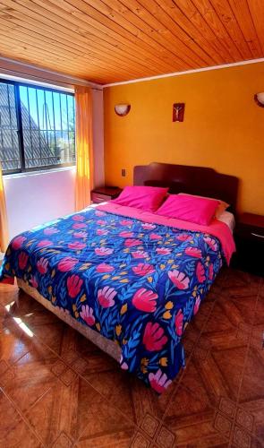 a bedroom with a large bed with a colorful blanket at Cabañas Jardín Alto in Pichilemu