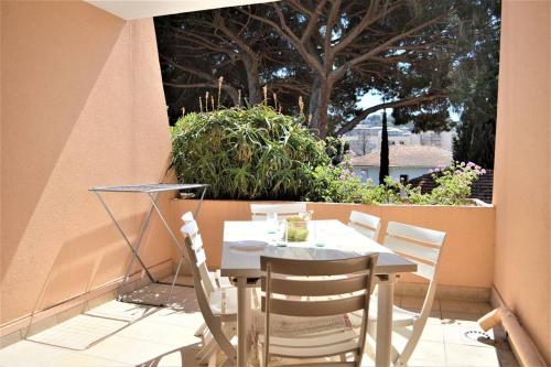 a table and chairs on a patio with a tree at Joli studio cabine à 500m plages in Cavalaire-sur-Mer