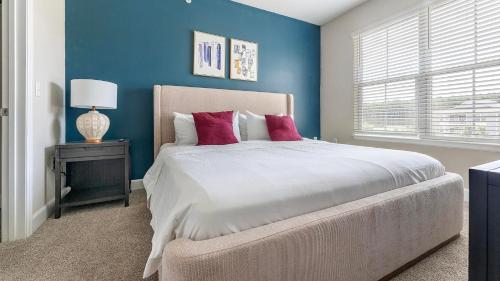 a bedroom with blue walls and a bed with red pillows at Landing Apartments - Summerville in Summerville