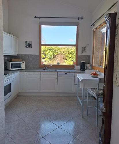 a kitchen with white cabinets and a window and a table at Villa Barbet in Lombez
