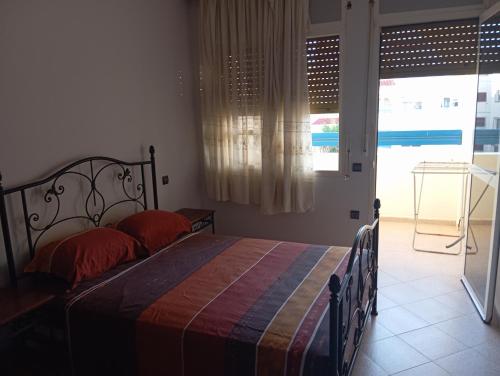 a bedroom with a bed with red pillows and a window at Arenabeach in Martil