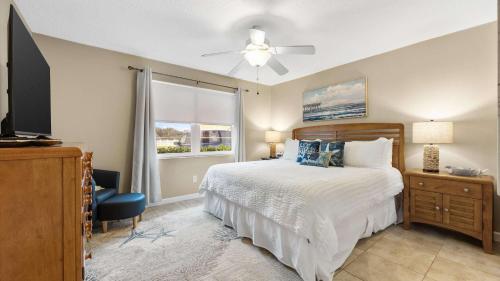 a bedroom with a bed and a tv and a window at Coastal Clipper - Charming 2 BDR Walk to Beach in St. Augustine