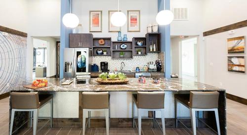 a kitchen with a large island with bar chairs at Landing at The Flats at Shadowglen - Manor in Manor