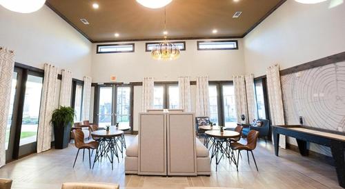 a lobby with tables and chairs and windows at Landing at The Flats at Shadowglen - Manor in Manor