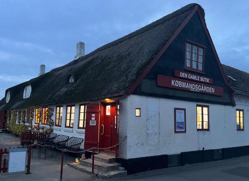 a building with a black roof and a red door at Købmandsgården, Ballen in Ballen