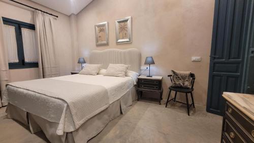 a bedroom with a large bed and a chair at El Garrotal de Medina in Carmona