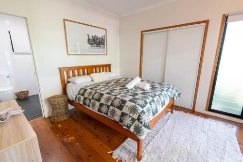 a bedroom with a bed and two windows at Straddie Hideout - Sleeps 9 - Pet Friendly in Point Lookout