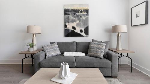 a living room with a gray couch and two tables at Landing at Station at Crestline - Mountain Brook in Mountain Brook