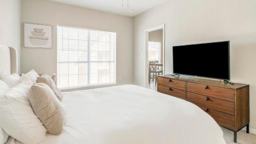 a bedroom with a white bed and a flat screen tv at Landing at Settlers Ranch - Pasadena in Houston