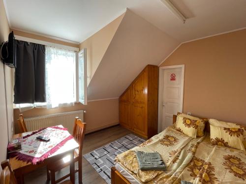a bedroom with a bed and a table and a window at Naomi vendégház in Sovata